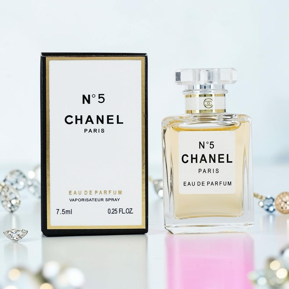 Nevora CHANEL N°5 Eau de Parfum 7.5ml travel spray bottle and its white and gold box on a reflective surface.