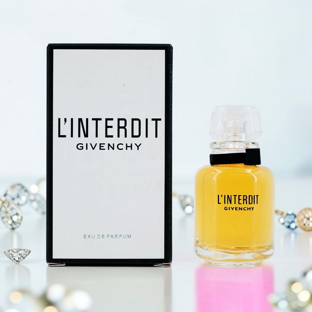 Nevora L'Interdit Givenchy Eau de Parfum bottle and box with black ribbon detail on a white surface with crystals