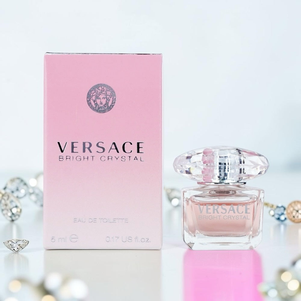 Nevora Versace Bright Crystal miniature perfume bottle and pink box with a crystal-inspired cap on a white surface.